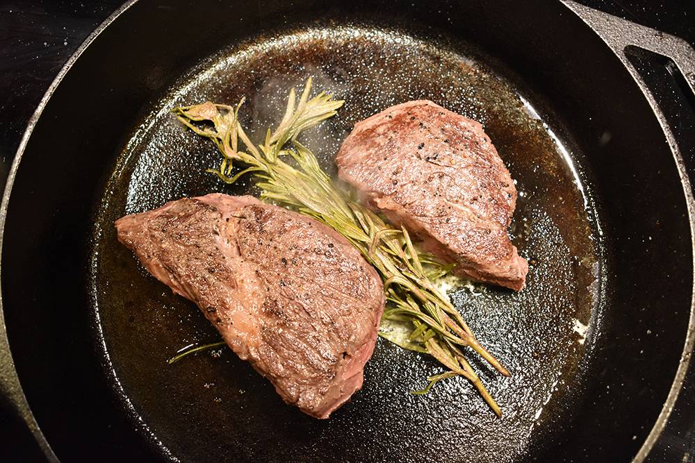 searing the steak in a cast iron pan